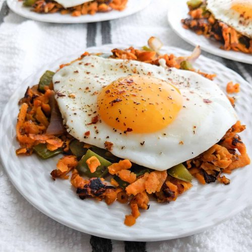 Fried egg over sweet potato hash served on a white plate and tablecloth - serves 4.