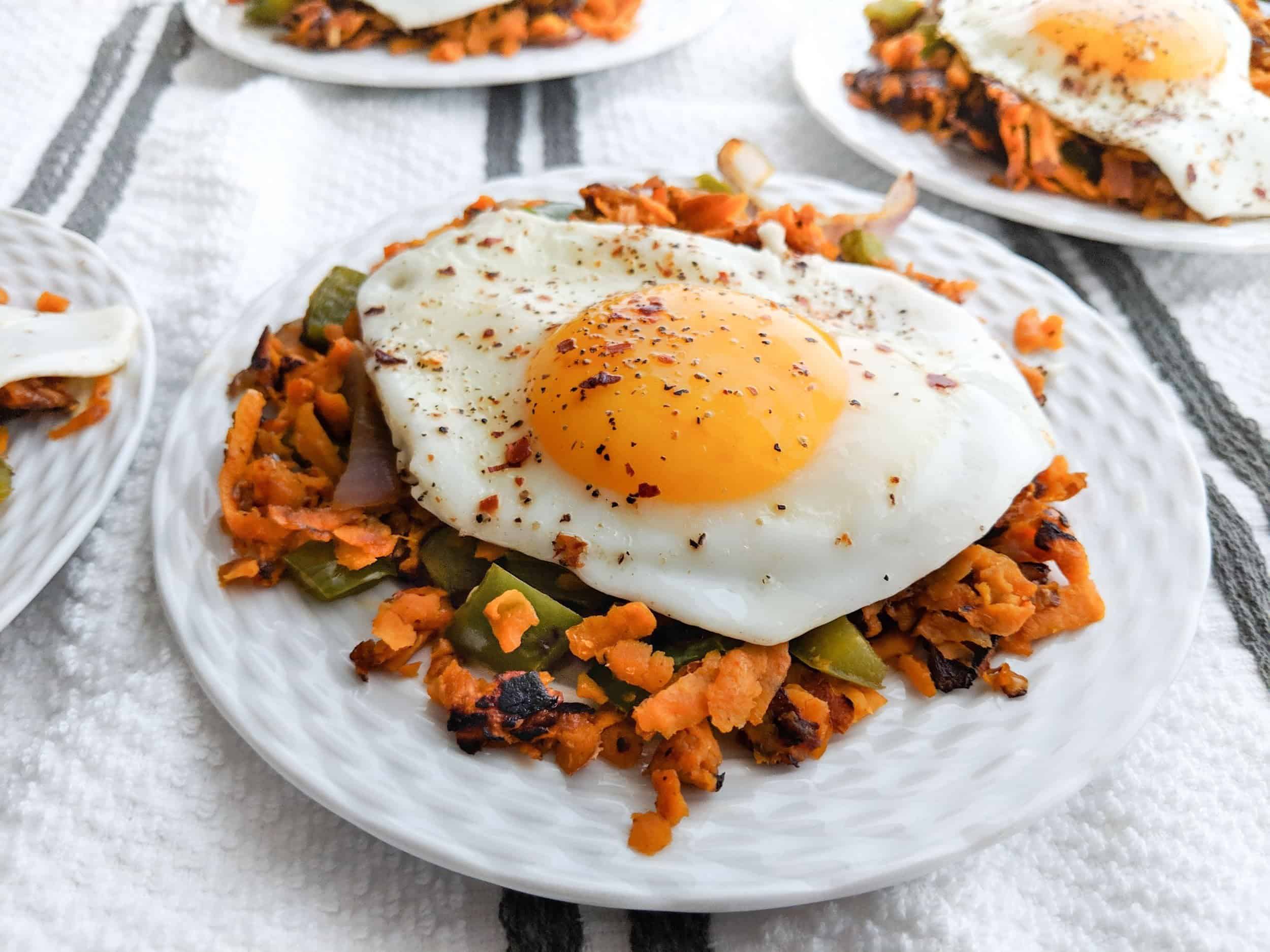 Fried egg over sweet potato hash served on a white plate and tablecloth - serves 4.