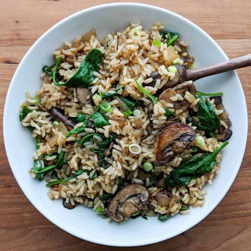 Asian mushroom rice with spinach served on a white dish