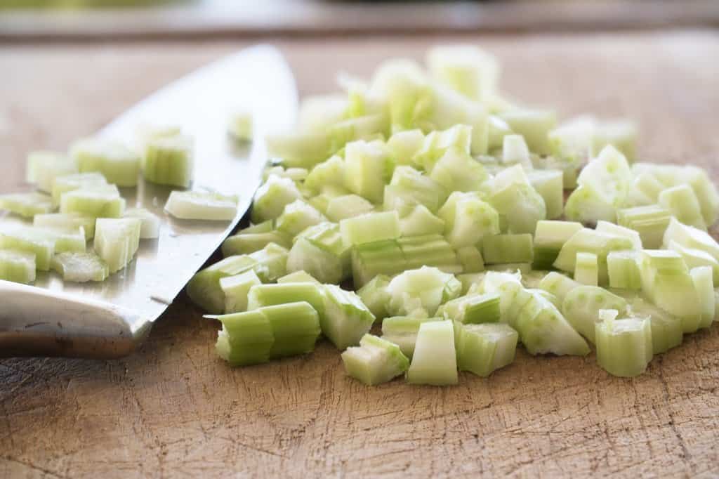 celery chopped in bite sized pieces on a wooden cutting board.