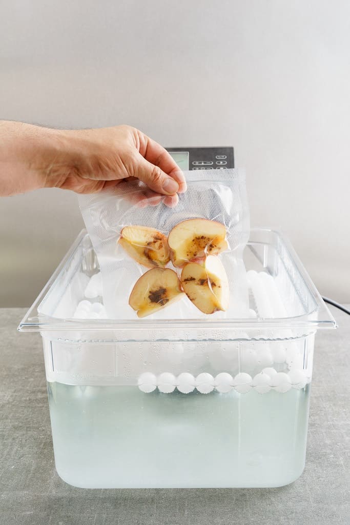 apples sealed in a bag and being cooked in a water bath sous vide style