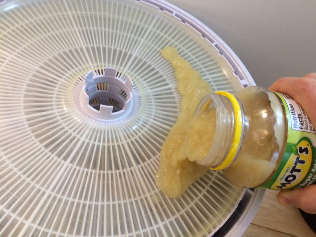 pouring applesauce on a dehydrator sheet
